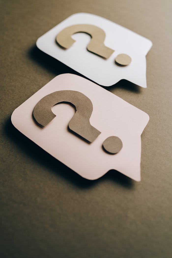 Two paper craft question marks on speech bubbles create a conceptual visual.